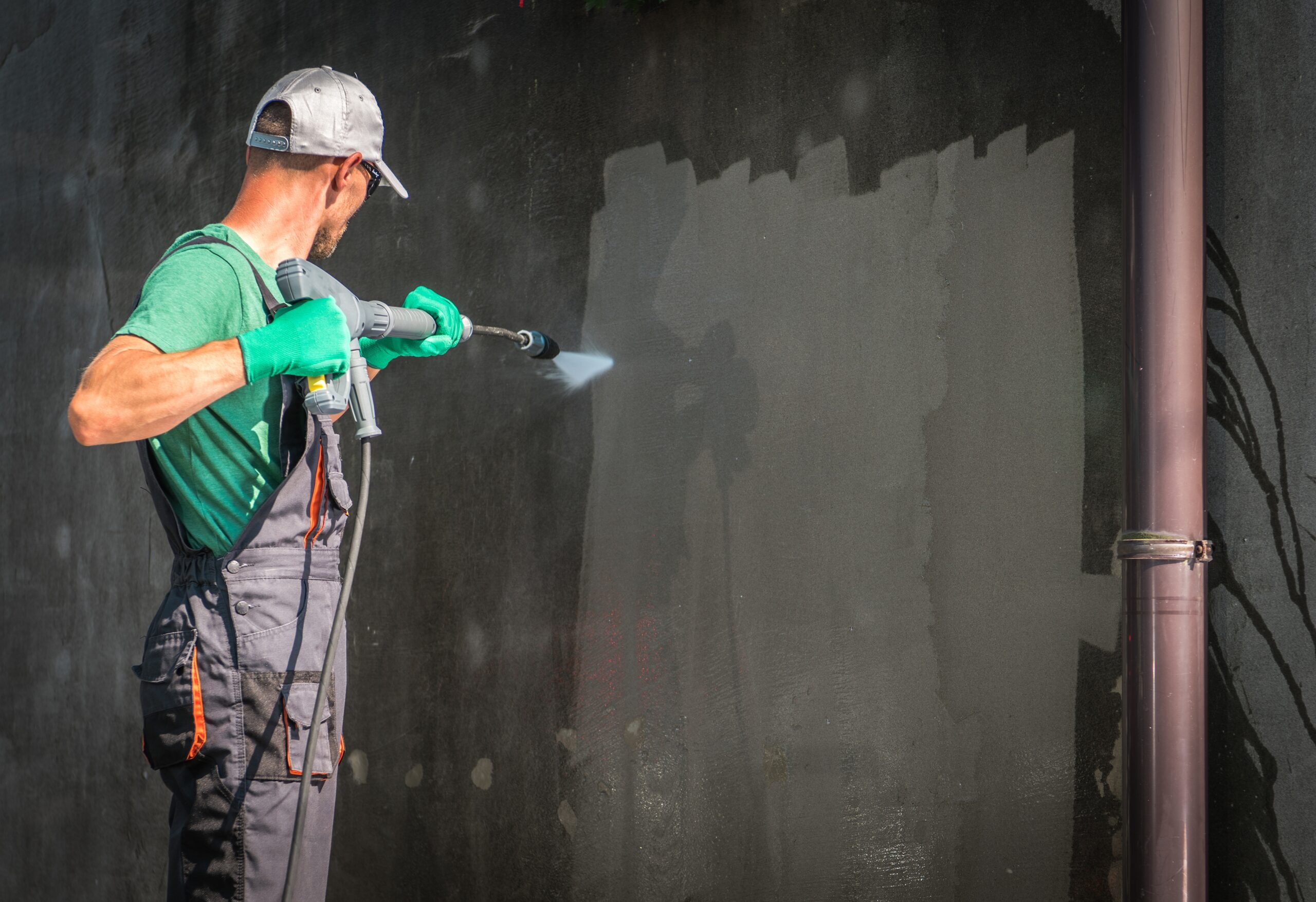 Building Elevation Pressure Washing by Worker with Power Washer. Refreshing House Outside Walls.