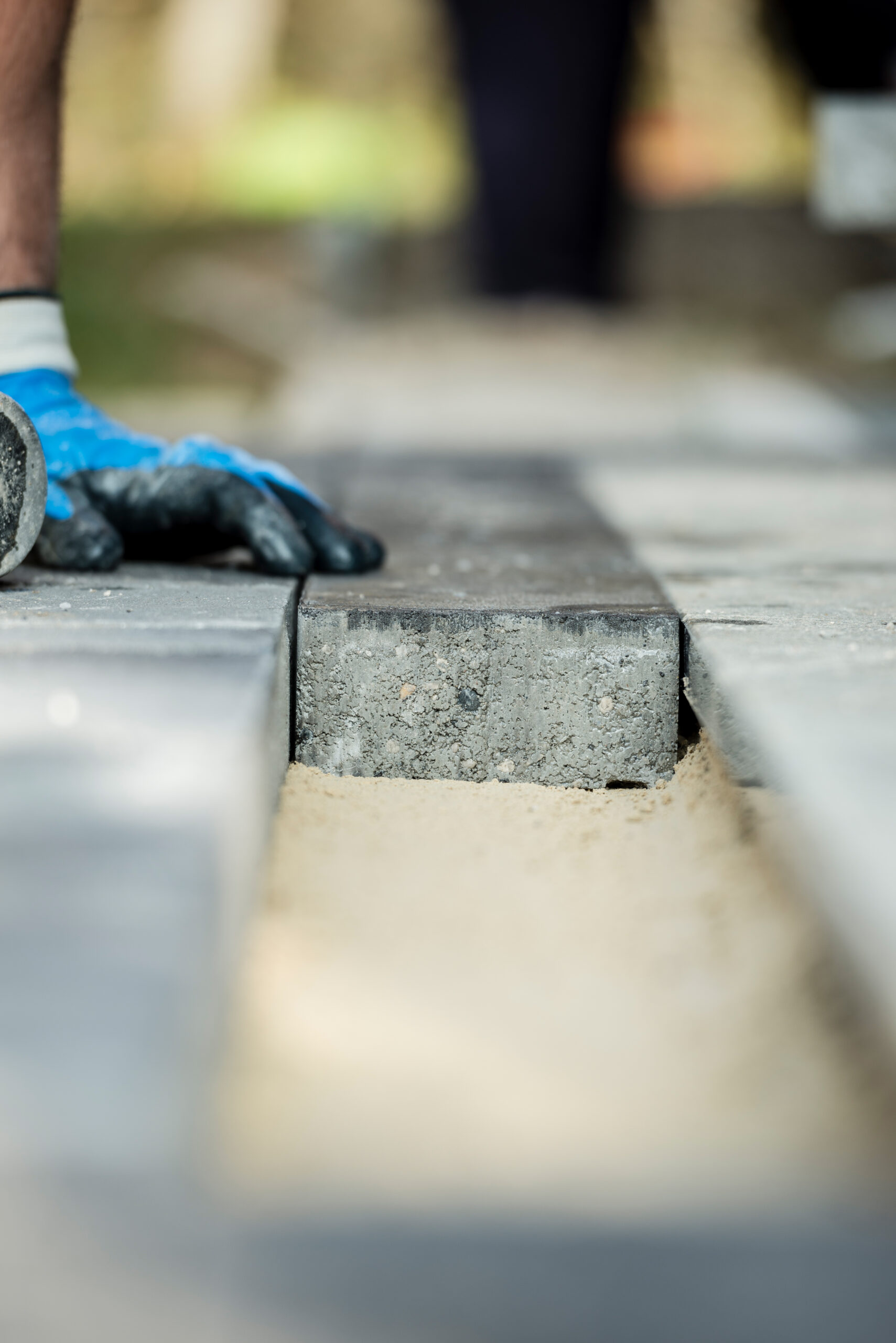 Manual worker installing paving block or stone in a closeup view.